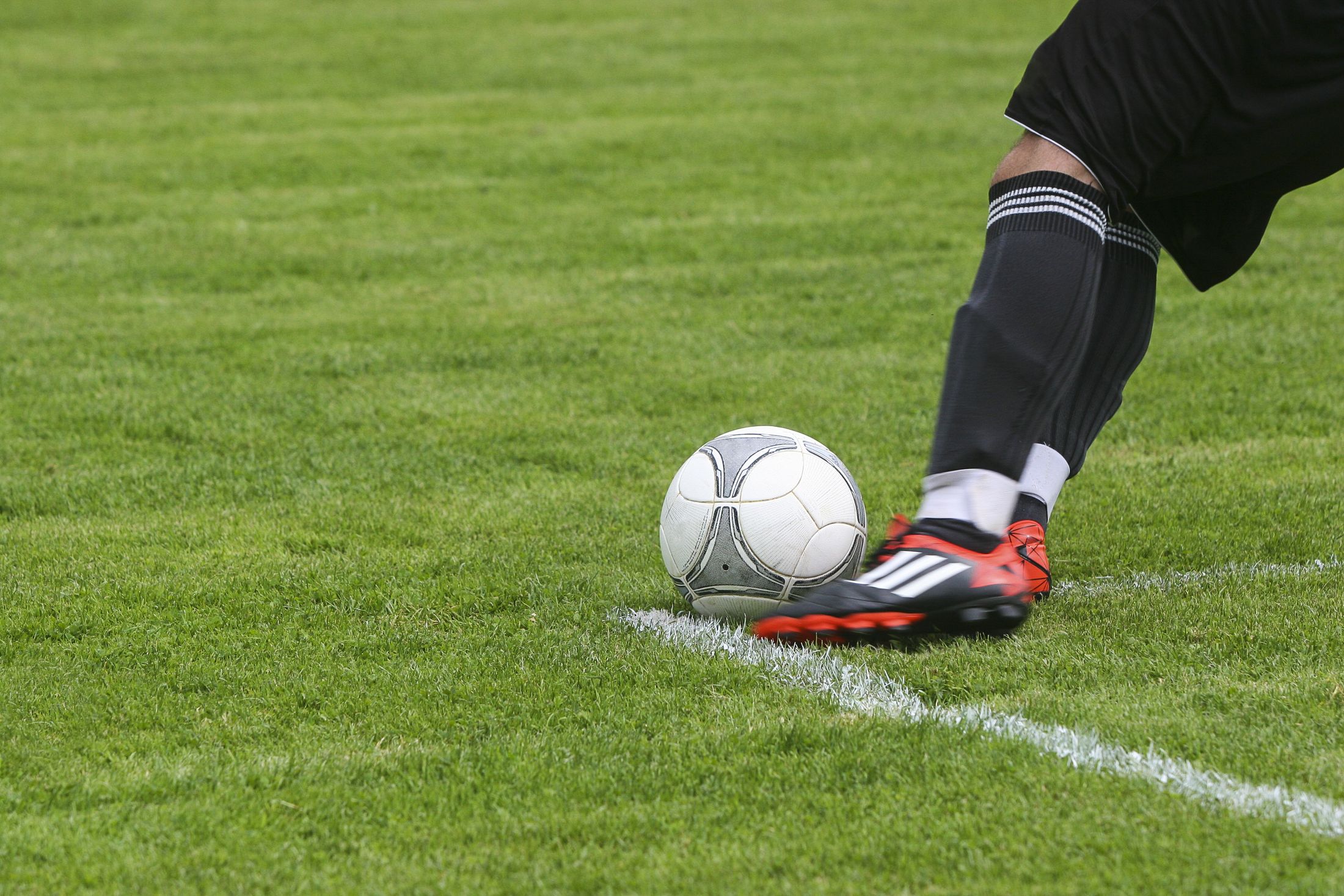 حذاء لاعب يضرب كرة فوق العشب